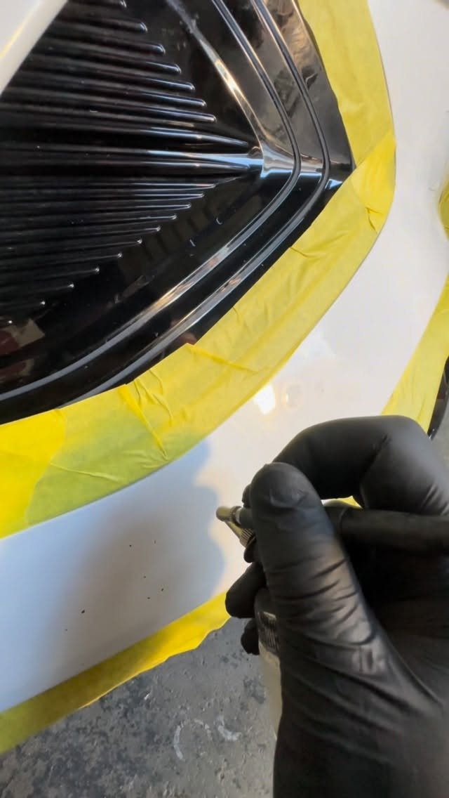 Profissional aplicando micro pintura em retoque com fita demarcada